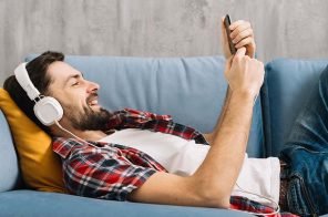 Um homem, deitado no sofá, com headphone, lendo um livro sobre o Harry Potter no aplicativo do Skeelo.